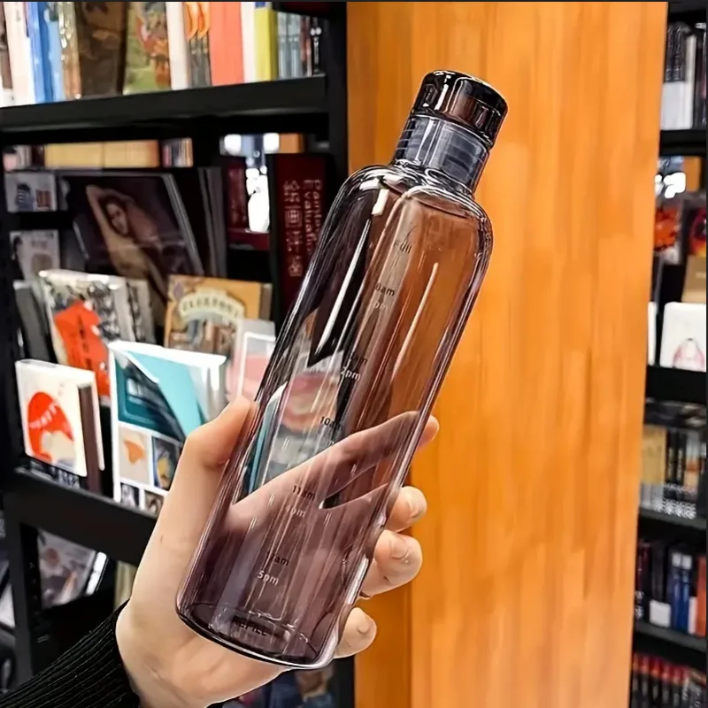 Hand holding a clear Vexo water bottle with measurement marks in a bookstore setting