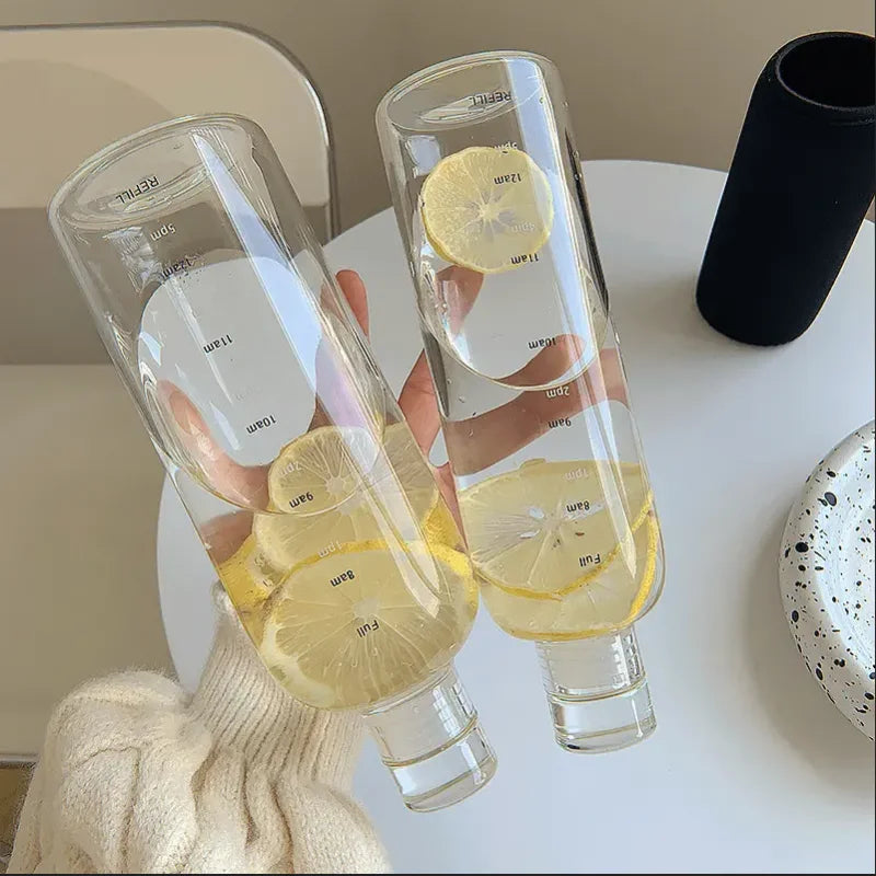 Two clear glass water bottles with lemon slices held over a white table, Vexo style